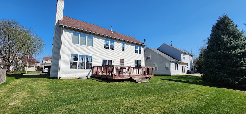rear view of house featuring a lawn, a wooden deck, and a chimney