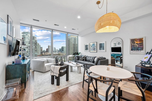 living area featuring expansive windows, recessed lighting, visible vents, and wood finished floors