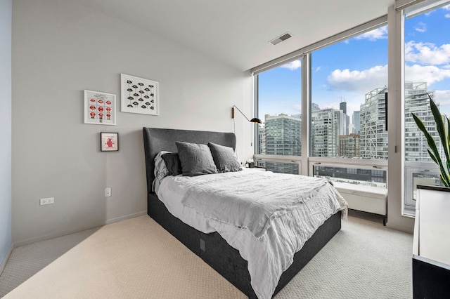 bedroom with carpet floors, visible vents, multiple windows, and a city view
