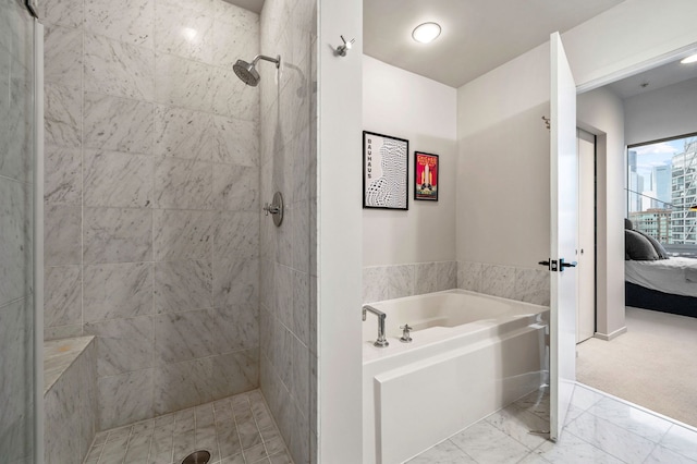 ensuite bathroom featuring a garden tub, marble finish floor, ensuite bath, and a tile shower