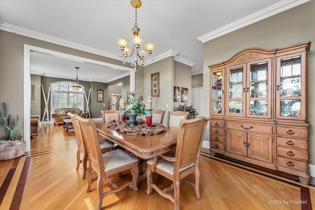 dining room featuring an inviting chandelier, light wood finished floors, and crown molding