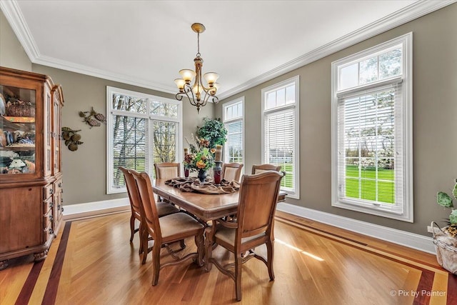 dining room with baseboards, a chandelier, ornamental molding, and light wood finished floors