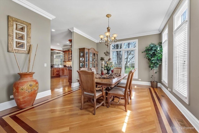 dining area featuring crown molding, visible vents, an inviting chandelier, baseboards, and light wood-type flooring