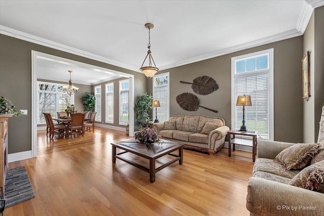 living area featuring crown molding, baseboards, a chandelier, and light wood finished floors