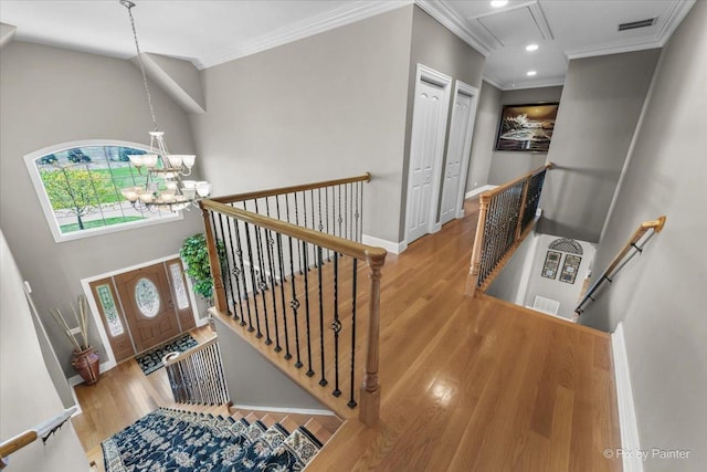 foyer entrance featuring ornamental molding, wood finished floors, and a notable chandelier
