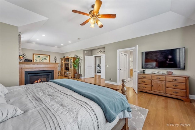 bedroom with a glass covered fireplace, baseboards, recessed lighting, and light wood-type flooring