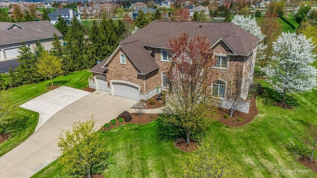 view of front of house with driveway, a garage, brick siding, a front lawn, and stone siding