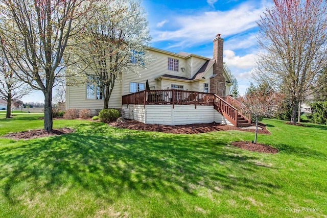 back of property with a wooden deck, a chimney, a yard, and stairway