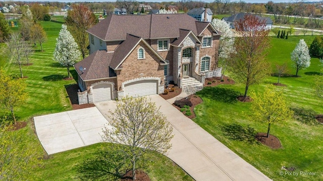 traditional-style home featuring a front yard, driveway, and stone siding