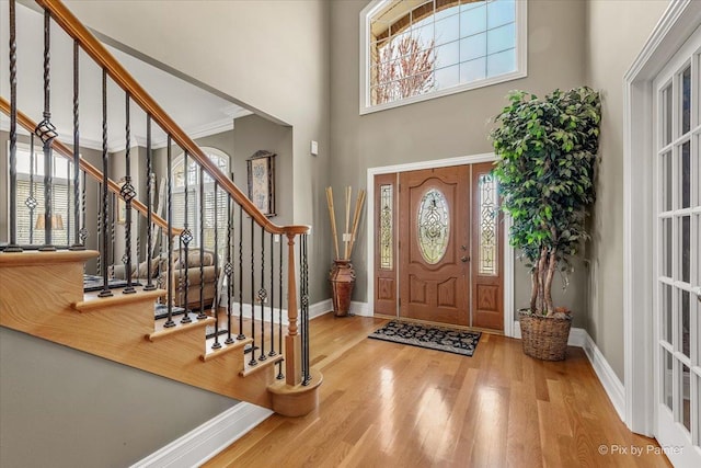 entryway featuring baseboards, wood finished floors, and stairway