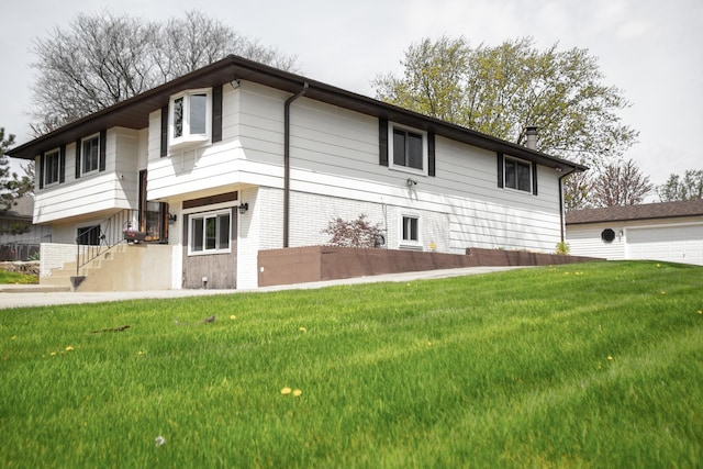view of side of home featuring a lawn, a chimney, a garage, and brick siding
