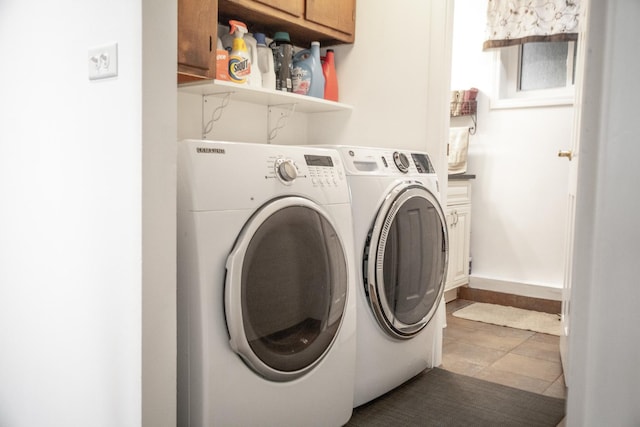 clothes washing area featuring washer and dryer, baseboards, and cabinet space