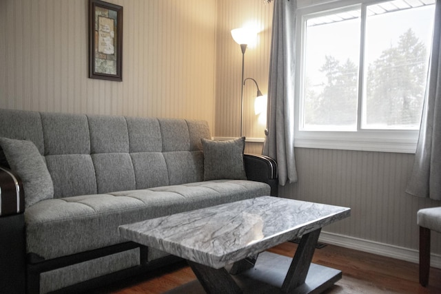 living room featuring baseboards, wood finished floors, and wallpapered walls