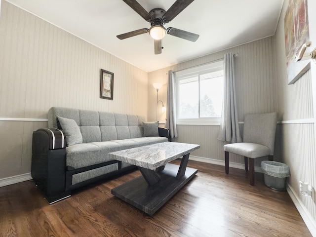 living area with baseboards, ceiling fan, and wood finished floors