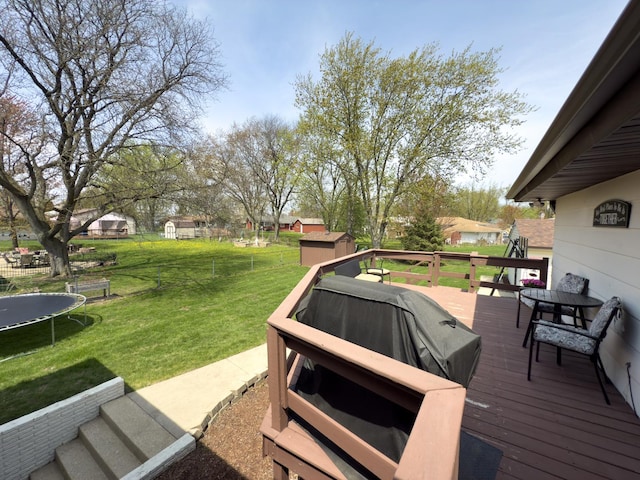 deck with area for grilling, a trampoline, an outdoor structure, a shed, and a yard