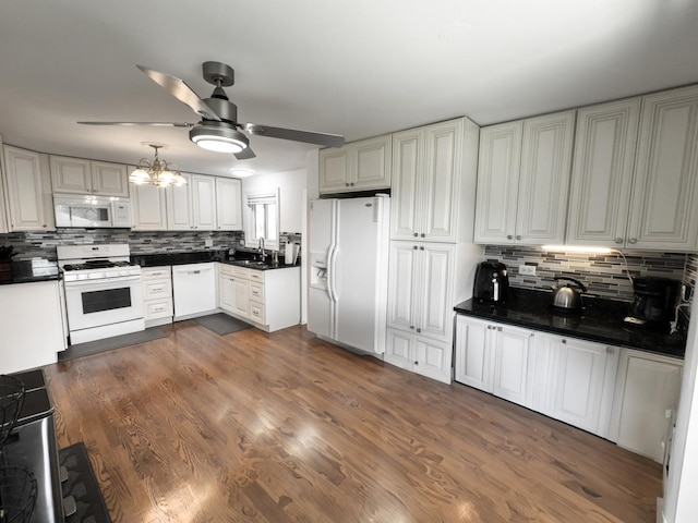 kitchen featuring white appliances, decorative backsplash, a sink, and ceiling fan with notable chandelier