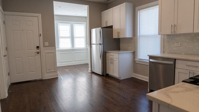 2957 N Avers Ave, Chicago, IL 60618 - kitchen with appliances with stainless steel finishes, white cabinets, decorative backsplash, dark wood-type flooring, and a decorative wall