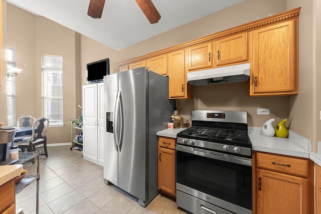 kitchen featuring light tile patterned flooring, appliances with stainless steel finishes, light countertops, a ceiling fan, and under cabinet range hood