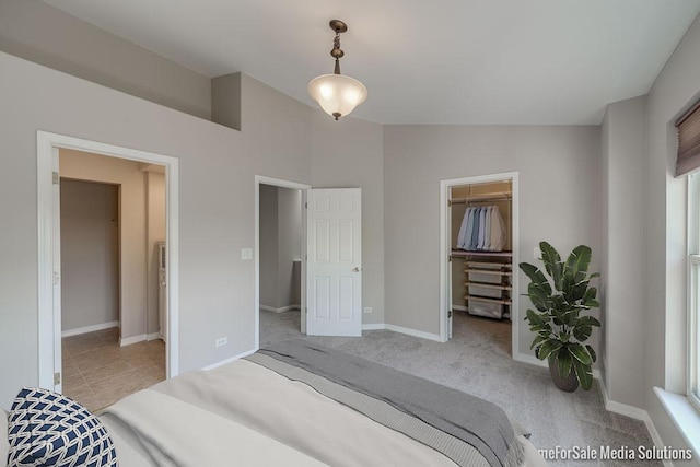 bedroom with baseboards, a spacious closet, a closet, and light colored carpet