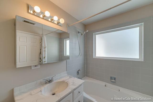 bathroom featuring shower / tub combo, vanity, and visible vents