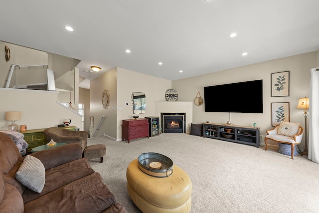 carpeted living area featuring a glass covered fireplace, recessed lighting, and stairs