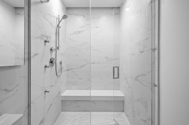 bathroom with a marble finish shower and toilet