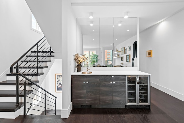 bar with beverage cooler, baseboards, wood finished floors, and stairway