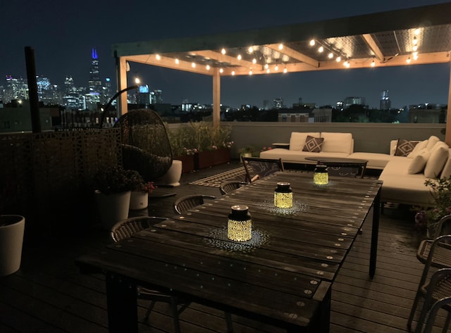 deck at night featuring an outdoor living space and a view of city lights