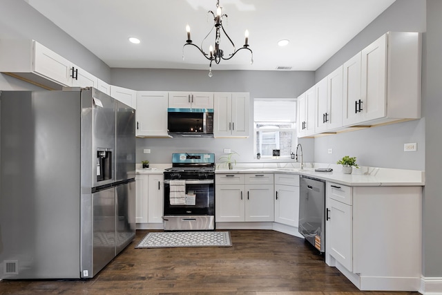 5068 W Congress Pkwy, Chicago, IL 60644 - kitchen featuring stainless steel appliances, a sink, a chandelier, white cabinets, and dark wood-style flooring