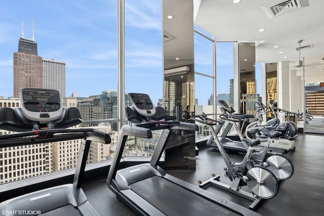 gym featuring visible vents, a city view, floor to ceiling windows, and plenty of natural light