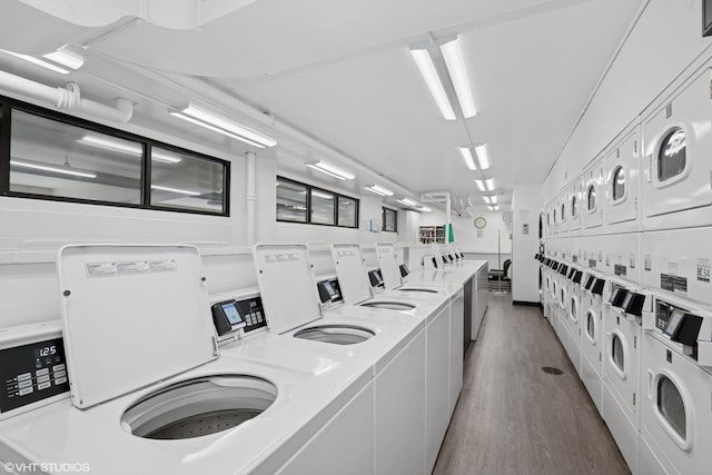 community laundry room featuring stacked washer and clothes dryer, dark wood-type flooring, and washer and dryer