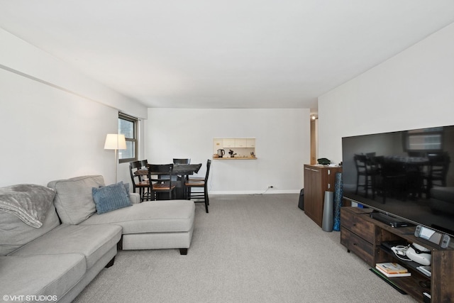 living area with baseboards and light colored carpet