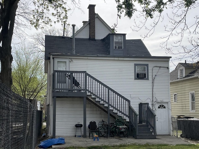 rear view of house with stairway, fence, central AC unit, and roof with shingles