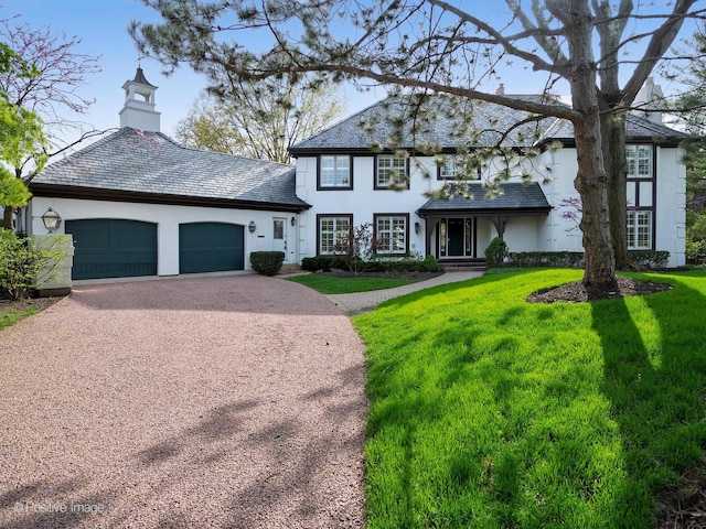 traditional-style home with a high end roof, a front yard, stucco siding, an attached garage, and driveway