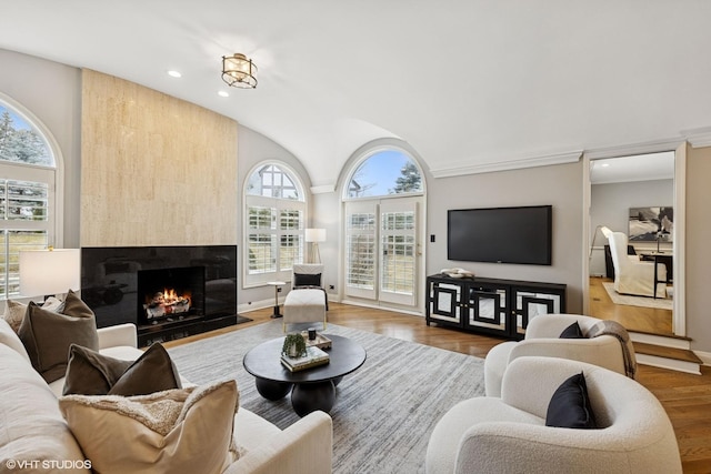 living area featuring a high end fireplace, vaulted ceiling, wood finished floors, baseboards, and recessed lighting