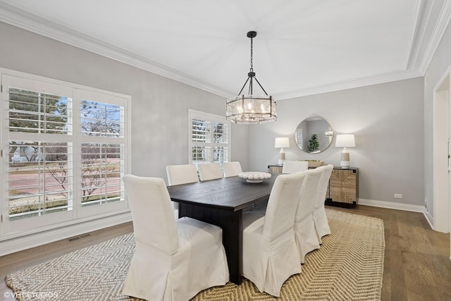dining room featuring crown molding, an inviting chandelier, baseboards, wood finished floors, and visible vents