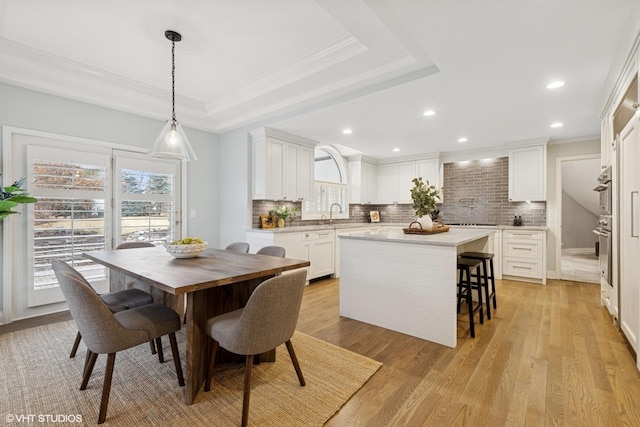 dining space with recessed lighting, ornamental molding, a raised ceiling, and light wood-type flooring