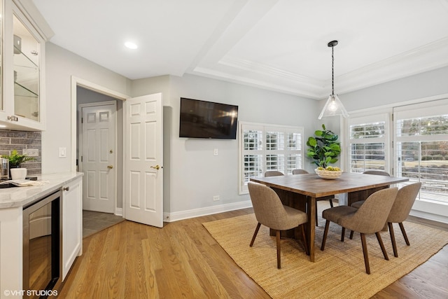 dining room with wine cooler, baseboards, light wood-type flooring, recessed lighting, and a tray ceiling