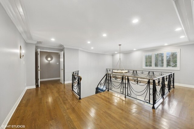 interior space featuring crown molding, wood finished floors, baseboards, recessed lighting, and a notable chandelier