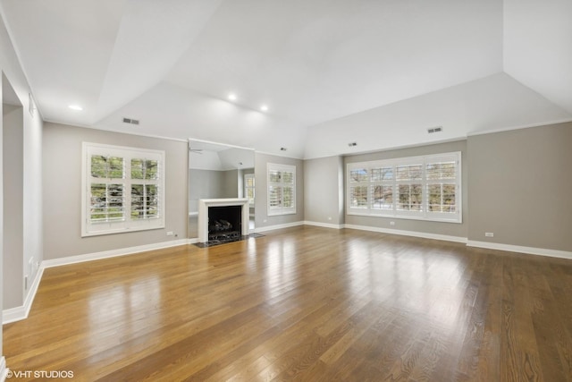 unfurnished living room with a fireplace with flush hearth, plenty of natural light, and wood finished floors