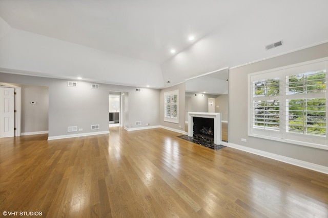 unfurnished living room with a fireplace with flush hearth, wood finished floors, and visible vents