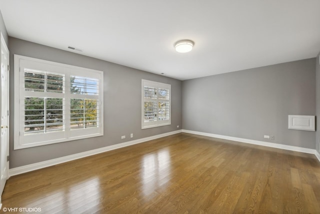 unfurnished room with baseboards, wood finished floors, and a wealth of natural light
