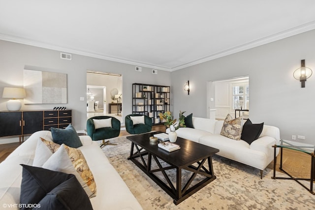 living room with baseboards, visible vents, ornamental molding, and wood finished floors