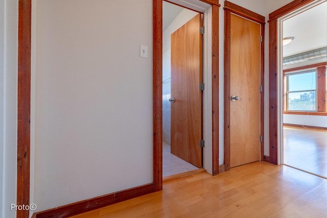 corridor featuring light wood-style floors and baseboards