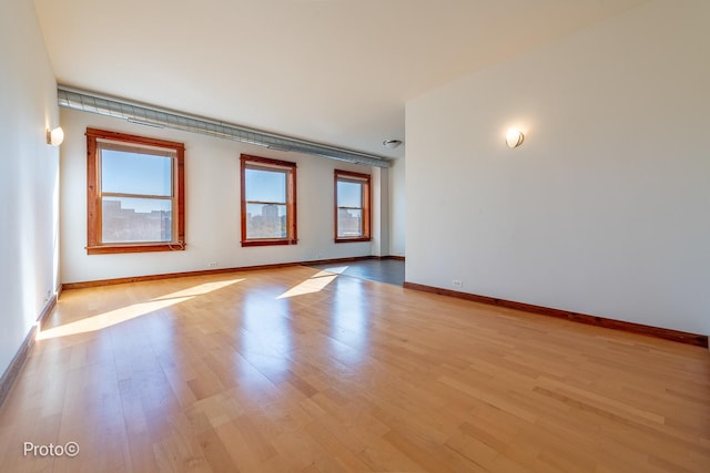 spare room featuring baseboards and light wood-style flooring