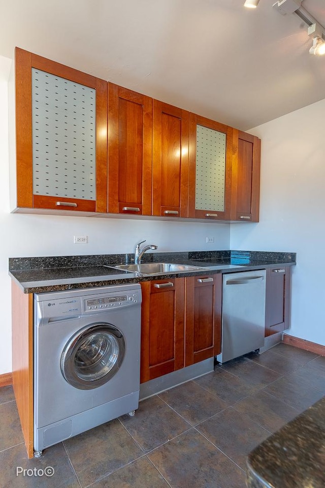 kitchen featuring baseboards, stainless steel dishwasher, brown cabinets, and washer / clothes dryer