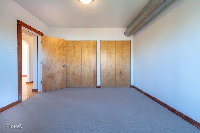 unfurnished bedroom featuring multiple closets, baseboards, and carpet