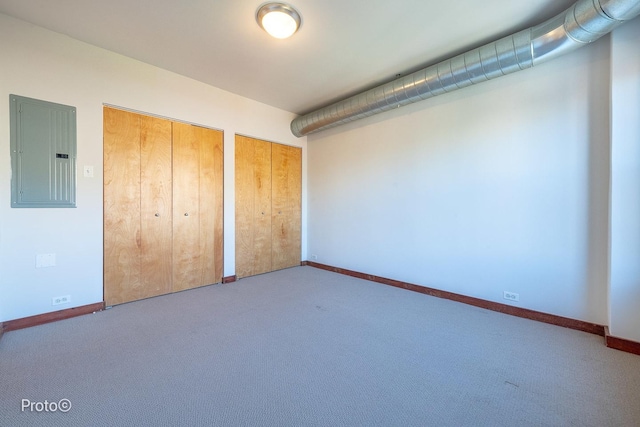 unfurnished bedroom featuring two closets, baseboards, carpet floors, and electric panel