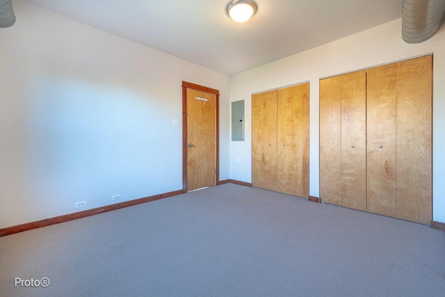 unfurnished bedroom with carpet floors, multiple closets, baseboards, and electric panel