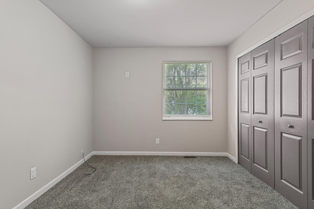 unfurnished bedroom featuring baseboards, carpet, and a closet